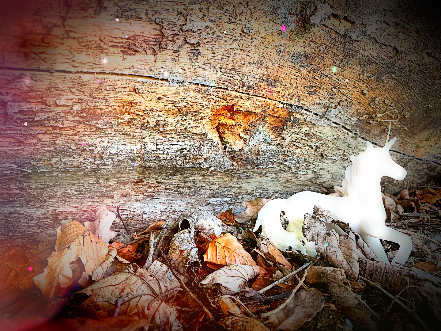 Unicorn standing in some leaves, in front of a fallen tree